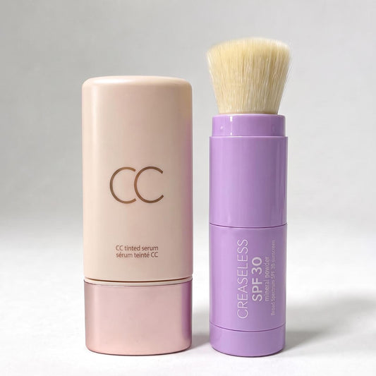 CC tinted serum in a pink bottle beside a purple SPF 30 mineral powder brush with bristles